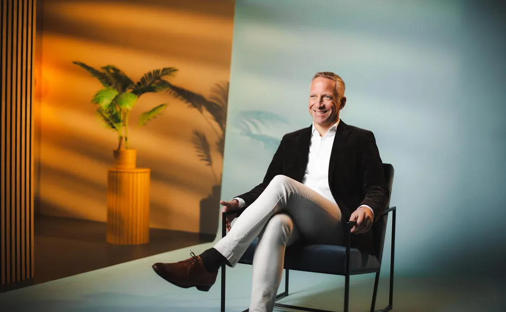 Interview-Look mit warmem Licht, Palme und heller Wand, Mann im Sessel