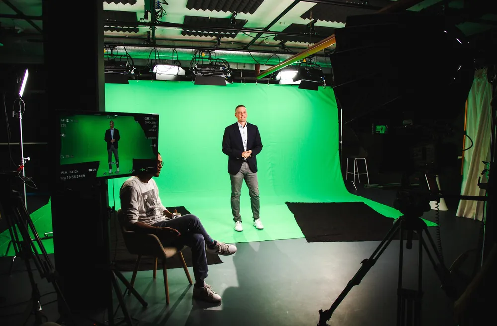 Greenscreen-Studio mit Mann vor grünem Hintergrund und Kameramonitor