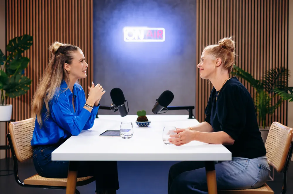 Zwei Frauen im Podcast am weißen Tisch mit On-Air-Schild
