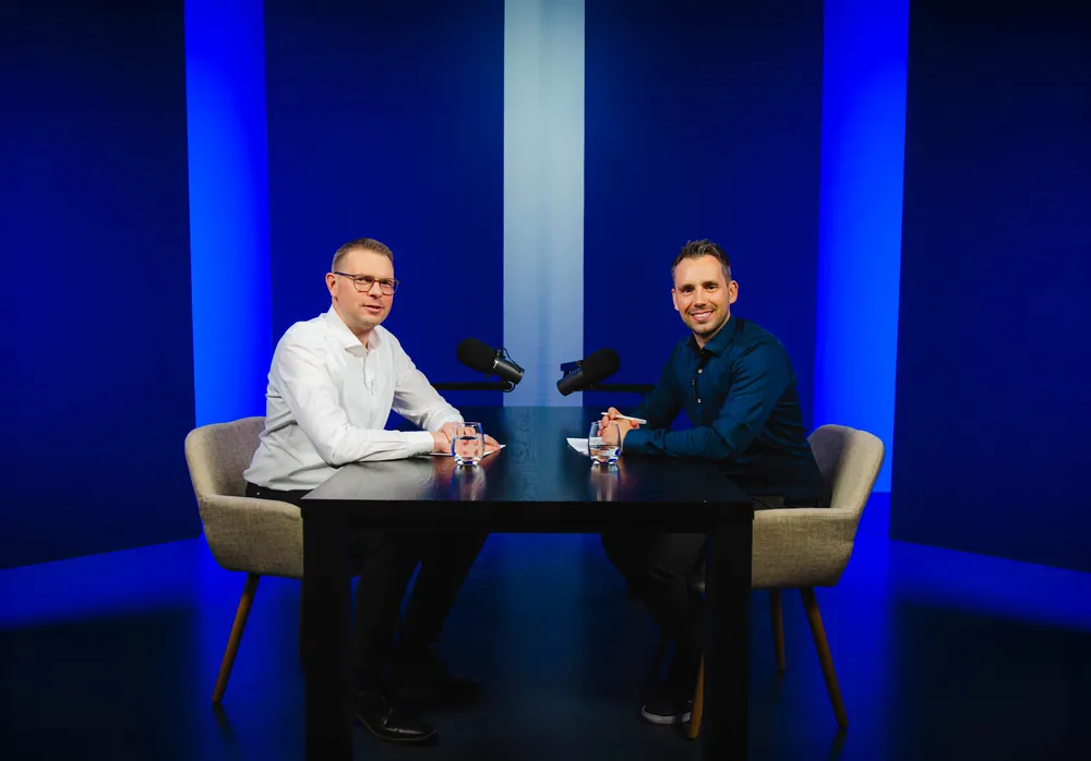 Podcast-Set mit tiefblauem Hintergrund und zwei Mikrofonen am Tisch