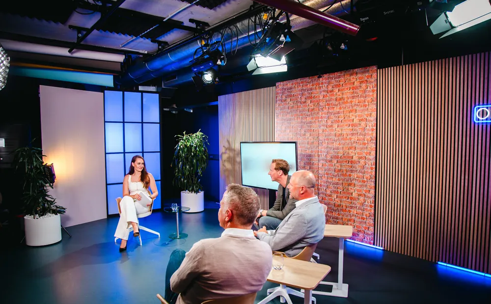 Talkrunde mit Moderatorin und drei Gästen vor Backsteinwand